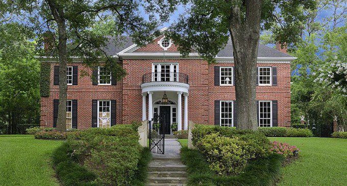 Red brick colonial mansion with white pillars around front door
