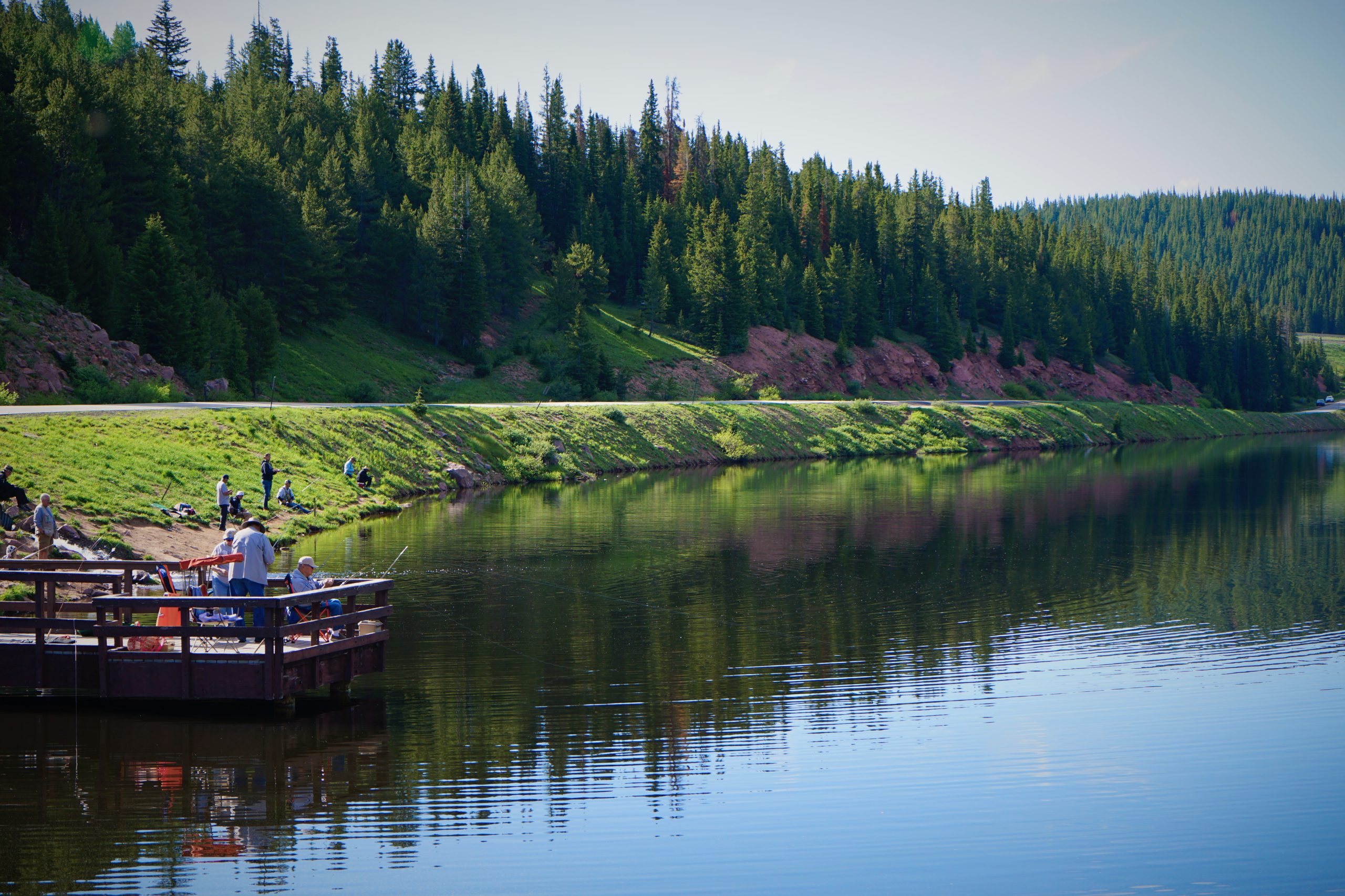 Deep blue lake with green mountain sides and a bridge into the water for fishing