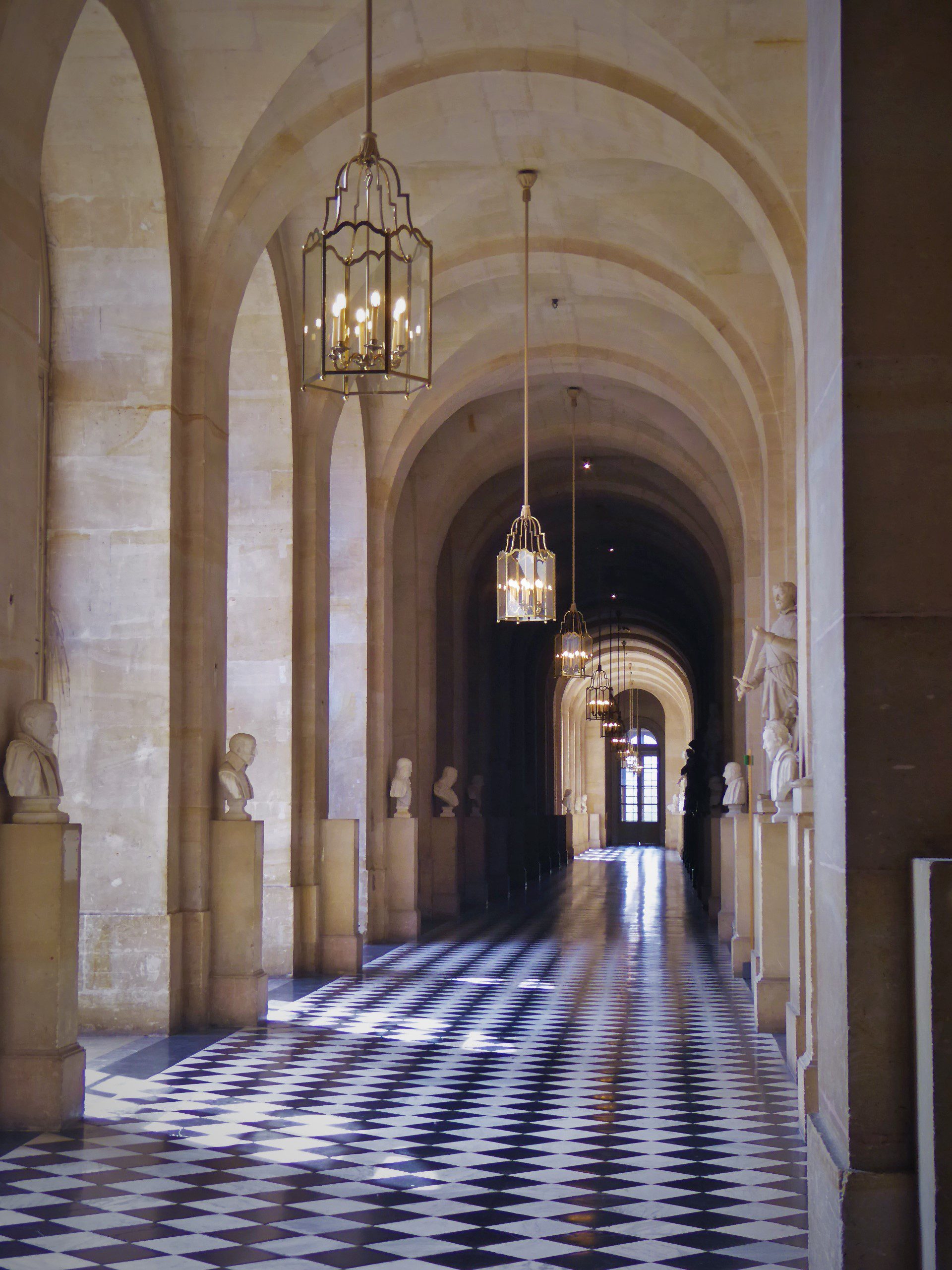 Hallway of museum lined with statues with light streaming in from the door