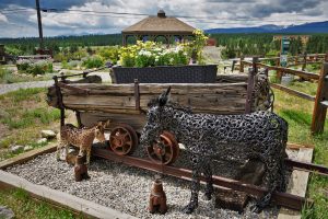 Iron statue of a burro by mining cart in mountain town
