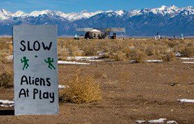 aliens at play sign near watchtower with mountains in background