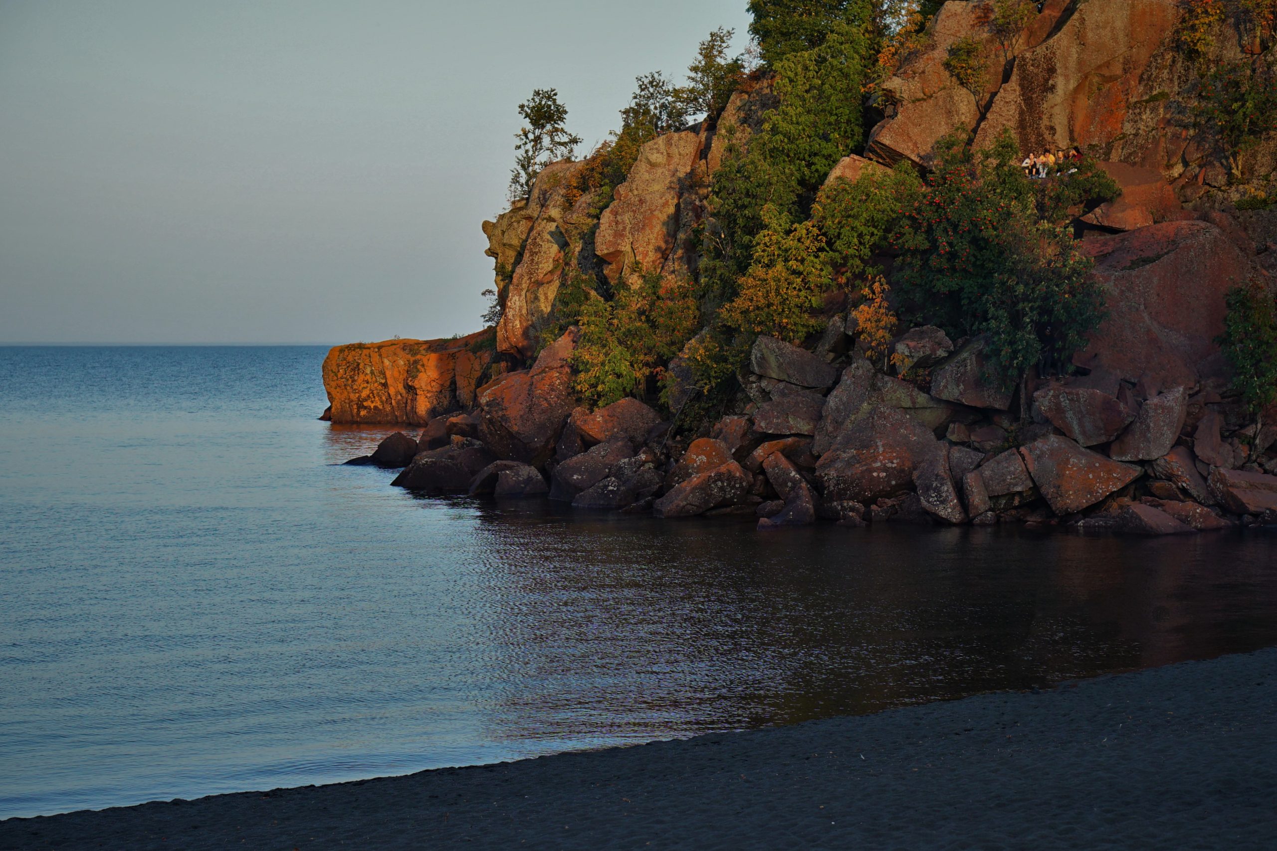 Sunset at a black sand beach with rock wall